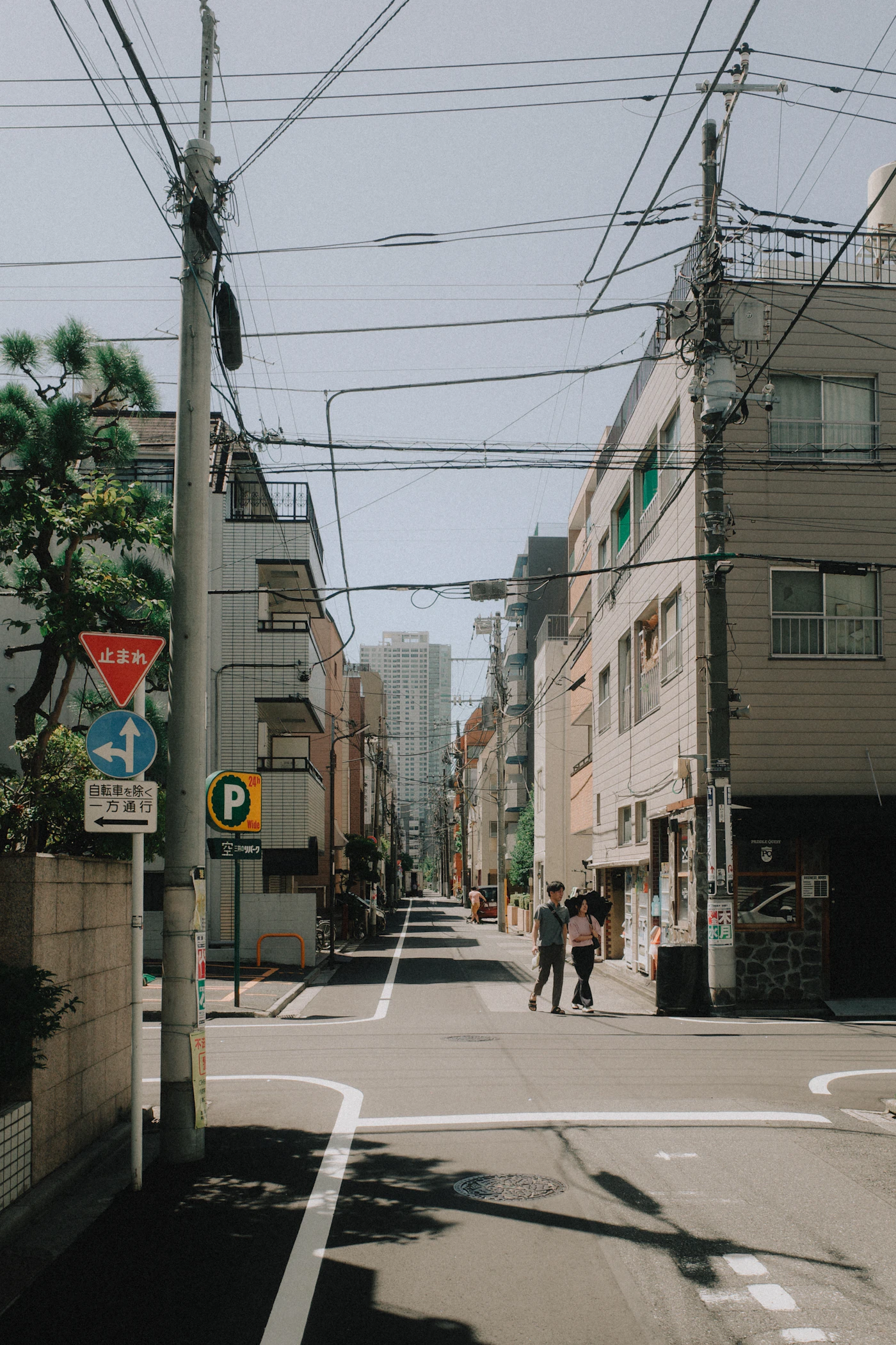 A quiet sunlit Tokyo neighborhood street with overhead wires